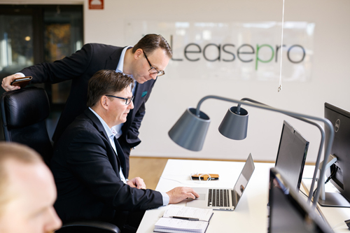 Två medarbetare på Leasepro samarbetar vid ett skrivbord